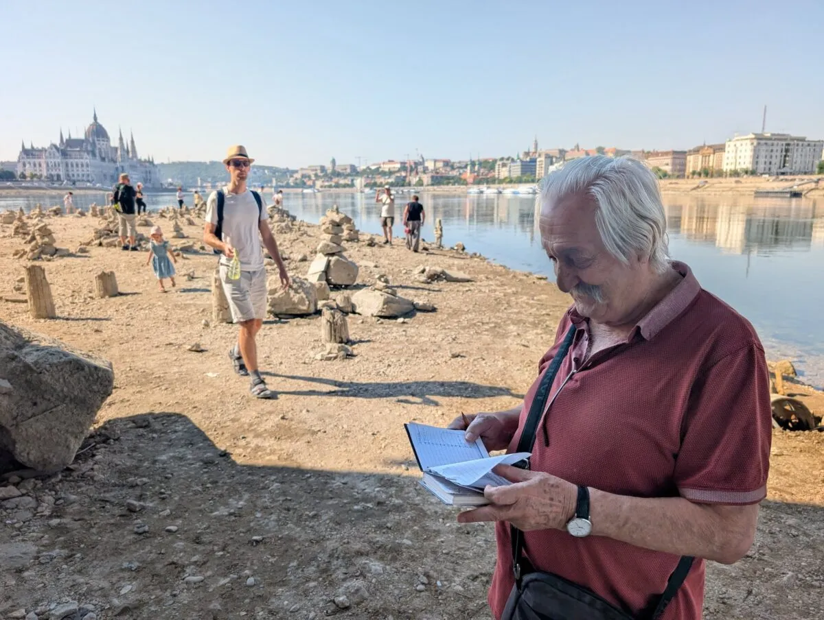 Local man measuring the exposed shore in his notebook